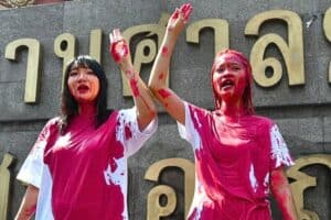 Two protesters covered in red paint
